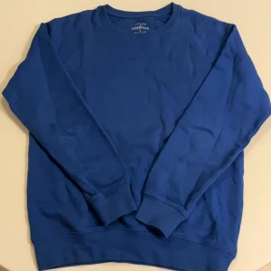 Blå sweatshirt från Race Marine - Blå crewneck sweatshirt från Race Marine Essentials i ekologisk bomull. Klassisk modell med rund hals och ribbade muddar vid ärmslut och nederkant. Perfekt för chill dagar och enkel att matcha med jeans eller joggers. Passar även om man har M.