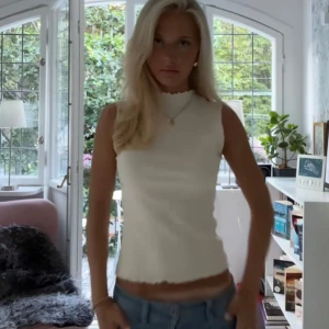 Vit ärmlös topp - Säljer en vit ribbad linnetopp med vågig kant vid halsringningen. Toppen är ärmlös och har en croppad passform som sitter snyggt till både jeans och kjol. Perfekt för varma dagar och enkel att styla med smycken🤗🥰❤️😍❤️❤️ helt oanvänd 