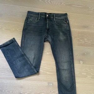 Replay jeans  - Snygga Replay jeans i mörkblå tvätt med klassisk femficksdesign och diskreta slitningar. Byxorna har raka ben, normal passform och detaljerad söm på bakfickorna. Märkespatch i läder baktill och dragkedjegylf. Perfekta för en stilren vardagslook. Jeansen passar till allt och är riktigt snygga, killen på bilden är ungefär 180cm lång och sitter perfekt på han, skicket är som nytt alltså perfekt och har använts ungefär 3 gånger, storleken är W32 L32, priset ej hugget i sten, hör av dig vid frågor!🤩