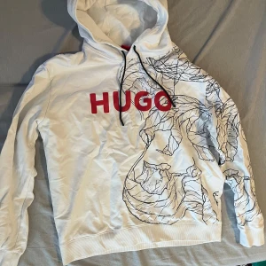 Vit hoodie från HUGO med print - Säljer en vit hoodie från HUGO. Använt ett par gånger bara. Storlek L men passar mig som har M också.