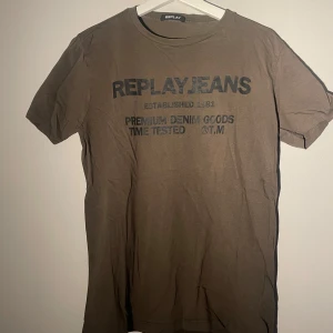  t-shirt från Replay Jeans - Snygg mörkgrön t-shirt från Replay Jeans med svart tryck framtill och en liten röd detalj på ärmen. Klassisk passform med rund hals och korta ärmar. Perfekt för en avslappnad stil. Vet inte storleken men skulle gissa på xs/s