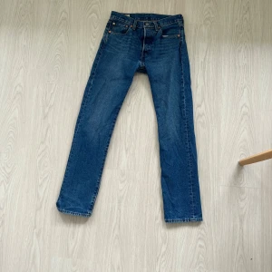 Levi's 501 blå jeans W29 L32 - Klassiska Levi's 501 jeans i blå denim med raka ben och knappgylf. Byxorna är i använt bra skick. Midjemåttet är 29 och längden är 32.