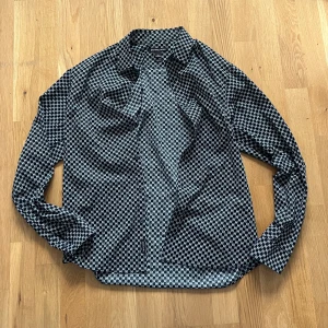 Michael Kors skjorta - Snygg svartvit skjorta från Michael Kors i slim fit-modell. Skjortan har ett grafiskt mönster med MK-loggor över hela tyget, långa ärmar och knäppning framtill. Perfekt för dig som gillar stilrena och trendiga plagg med en exklusiv känsla. Passar M. Äkta. Information, bilder och prisdiskutering i dm.