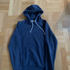 Pier one hoodie - Säljer en mörkblå hoodie från pier one med vit snörning i huvan och stor magficka framtill. Tröjan har lång ärm och är gjord i mjuk bomull, perfekt för chill dagar eller när du vill vara extra bekväm.