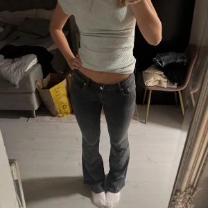 Svarta bootcut jeans med låg midja - Säljer ett par svarta jeans med bootcut-modell och låg midja. Jeansen har klassisk femficksdesign och är i ett mjukt denimtyg som sitter snyggt över höfterna och låren. 