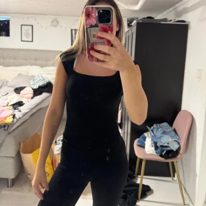 Svart mjuk t shirt  - Säljer en svart, tight och T-shirt med fyrkantig ringning. Toppen har en enkel och stilren design som passar perfekt till jeans eller kjol. Materialet känns mjukt och följsamt mot kroppen.