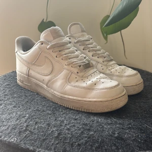 Nike Air Force 1 vita sneakers - Klassiska vita Nike Air Force 1 sneakers i skinn med lågt skaft och snörning. Perfekta för dig som gillar streetstyle och vill ha en tidlös sneaker i garderoben. Storlek 41