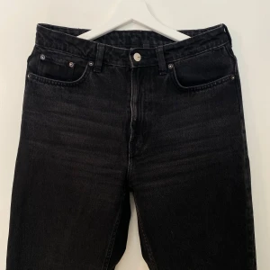 Svarta raka jeans  - Snygga svarta jeans med klassisk femficksdesign och raka ben. Jeansen har mellan/hög midja och är tillverkade i robust denim med en lätt tvättad look. Perfekta för dig som gillar en clean och tidlös stil. ”Voyage” från Weekday storlek 29/32.