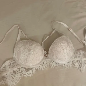 Vit spetsig bh - Superfin vit bh med spetsdetaljer och justerbara axelband. framsidan har vackert blommigt spetsmönster och en bred spetskant nedtill. Står inte exakt storlek på men det är en A-kupa gissar jag på😊(Skickar tyvärr bara iväg via instabox)😊