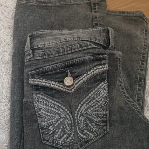 Lågmidjade jeans ifrån Gina tricot  - Lågmidjade bootcut jeans ifrån Gina tricot i storlek 146. Flared jeans med brodering på baksidan. Säljer då den inte kommer till användning längre. Knappen har börjat rosta lite smått på baksidan men inget märkvärdigt. Se bild. 