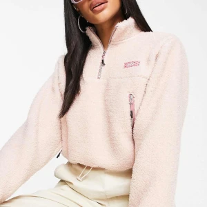 Ljusrosa fleece hoodie från Nike - Supermjuk och fluffig ljusrosa fleece hoodie från Nike med half zip och hög krage. Tröjan har en liten bröstficka med dragkedja och broderad Nike-logga i rosa. Perfekt för kyliga dagar och riktigt cozy vibes.