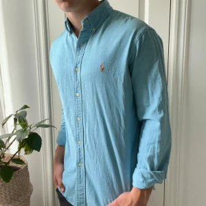 Ralph Lauren skjorta slim fit.  - Ralph Lauren Oxford slim fit. Inga större defekter förutom en fläck vid armen som ni ser. Vet ej om den går bort men märks inte vid användning. Modellen bär L och är 180,75 kg. Skön skjorta! 