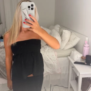 Svart bandeau tubtopp - Säljer en svart bandeau tubtopp med volangliknande fall nedtill. 