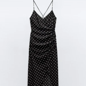 Svart prickig långklänning från Zara - Svart långklänning med vita prickar och smala axelband. Omlottmodell med draperad effekt i midjan och slits framtill. Aldrig använd🤗