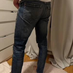 Dondup, Blå slitna jeans med raka ben - Säljer ett par blå jeans med slitningar och hål på benen för en cool, avslappnad look. Jeansen har raka ben, klassiska bakfickor och snygga detaljer med kontrastsömmar. Perfekta för dig som gillar streetstyle och vill ha ett par jeans med attityd.Exklusivt märke Dondup, nypris 3100 kr