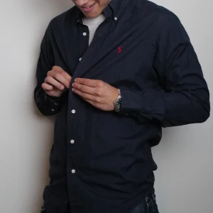 Mörkblå skjorta från Ralph Lauren - Klassisk mörkblå skjorta från Ralph Lauren med vit knappstängning och röd broderad logga på bröstet. Pris kan diskuteras 🙂👌