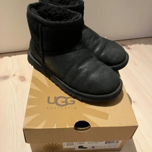 Svarta UGG boots storlek 36 - Klassiska svarta UGG boots i mjukt fårskinn med fluffigt foder och platt sula. Perfekta för kalla dagar, supermysiga och lätta att dra på. Rund tå och enkel design som funkar till allt. Storlek 36 innermått ca 23,3.