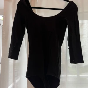 Svart body med trekvartsärm från Gina Tricot - Säljer en svart body från Gina Tricot med trekvartsärmar och rundad halsringning. Bodyn har tryckknappar i grenen för enkel på- och avtagning. Perfekt att styla med jeans eller kjol.