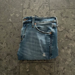 Jack and Jones jeans med slitningar - Säljer nu dessa Jack and Jones jeans med slitningar| Skick 7/10 har hål längre ner på benen| Skriv vid funderingar|