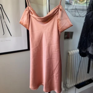 Rosa Satinklänning från Topshop - Säljer en rosa klänning i storlek 36 med tunna axelband och större band som sitter nedanför axlarna. Från Topshop