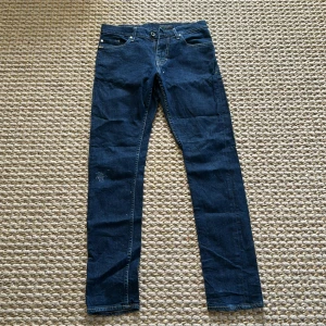 Mörkblå jeansbyxor från Tiger of Sweden - Säljer ett par klassiska mörkblå jeans från Tiger of Sweden, modell Pistolero. Byxorna har fem fickor, raka ben och normal passform. Perfekta för dig som gillar stilrena och tidlösa jeans.