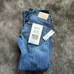 Blå Replay jeans 573 - Säljer ett par blå jeans från Replay, modell 573. Klassisk femficksdesign med snygga detaljer på bakfickan och Replay-lapp i midjan. Jeansen har normal passform och raka ben, perfekta till vardags. Märkeslapp och tags sitter kvar. W31 L32