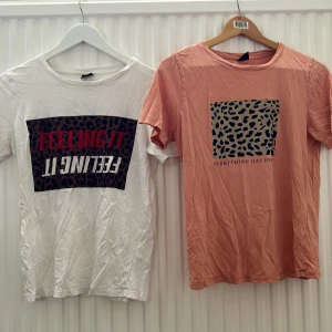 T-Shirt  från Gina Tricot - Vit t-shirt från Gina Tricot med leopardmönstrad ruta och texten 'FEELING IT' i rött. T-shirten har rund halsringning och korta ärmar. Perfekt för en trendig och avslappnad stil.