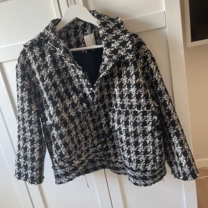 Svartvit rutig kavaj - Säljer en svartvit rutig kavaj med krage och lång ärm. Jackan har en klassisk tweed-look och är perfekt för att lyfta en outfit. Stängs framtill och har en lite croppad passform.