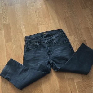 Svarta jeansbyxor från Lee - Säljer ett par svarta jeansbyxor från Lee med klassisk femficksdesign och dragkedja. Byxorna har raka ben och normal passform, perfekta till vardags. Tidlös modell som passar till mycket.