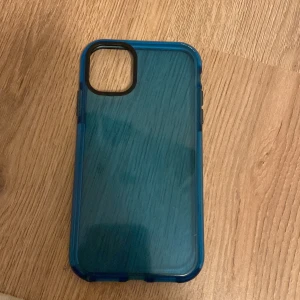 Blått mobilskal med transparent baksida - Säljer ett snyggt mobilskal med blå ram och transparent baksida. Skalet har öppning för kamera och passar perfekt för dig som vill skydda din mobil med stil.