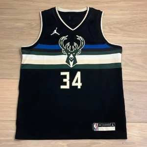 Basketlinne från Nike  - Säljer ett svart Milwaukee Bucks basketlinne med nummer 34 och Antetokounmpo på ryggen. Linnet har vita och gröna detaljer, NBA-logga och är tillverkat i Dri-FIT material för extra komfort. Perfekt för basketfans. Nypris är 1000 kr. Den är oanvänd och felfri. Pris går att diskutera.