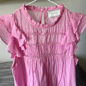 Rosa volangblus från Neo Noir - Supersöt rosa blus från Neo Noir med volangdetaljer på ärmarna. Blusen ser nästan helt oanvänd ut och är i en så fin färg. Köpt för 699 och finns inte att hitta längre. Perfekt för vår och sommar!