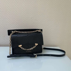 Svart axelväska från Karl Lagerfeld - Snygg svart axelväska från Karl Lagerfeld i croco-mönstrat skinn. Väskan har guldfärgad kedja som detalj och justerbar axelrem. Perfekt storlek för det viktigaste och stängs med magnetlås. Mått: cirka 15x21.