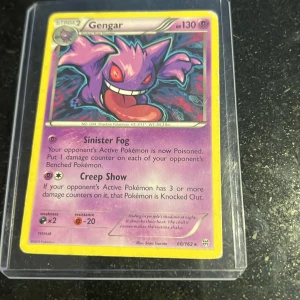 Gengar (Pokémonkort) - Samlarkort med Gengar, en populär Pokémon. Kortet har 130 HP och innehåller attacker som Sinister Fog och Creep Show. Perfekt för dig som gillar Pokémon och vill utöka din samling med ett coolt och klassiskt kort.