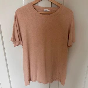 Beige/rosa t-shirt från Filippa K - Säljer en enkel och stilren beige t-shirt från Filippa K i storlek M. T-shirten har rund halsringning och korta ärmar, perfekt för en avslappnad look. Tillverkad i mjukt bomullsmaterial.