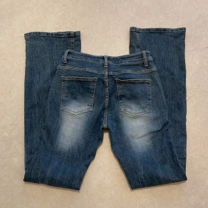 Blå bootcut jeans - Säljer ett par klassiska blå bootcut jeans med lätt slitning på framsidan och baksidan. 