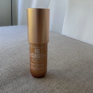 Glowmotions Rio Sunset Glow Oil - Glowmotions Rio Sunset Glow Oil från Sol de Janeiro är en skimrande kroppsolja i en lyxig guldig/bronsig nyans. Kommer i en elegant flaska med guldlock och ger huden en solkysst glow med lyster. 75ml flaska. har inte plasten kvar men oanvänd. 
