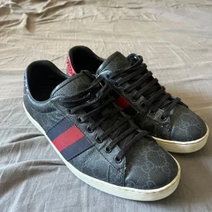 Gucci Ace Skor - Gucci Ace Skor | Skicket är 9,5/10 - Storlek 42- Nypris 7499kr - Mitt pris 2450, skorna är i väldigt bra skick, enda är lite deffekt på Gucci loggan på hälarna annars är dom nya. Endast skor ingår, skorna är sälfallet äkta! Pris kan diskuteras!