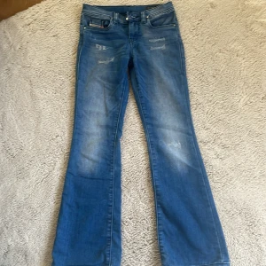 Marinblå diesel jeans (low waist)  - Säljer ett par blå bootcut jeans från Diesel, modell Lowleeh. Jeansen har klassisk femficksdesign, slitna detaljer framtill och en snygg tvätt. Perfekta för dig som gillar en lite utsvängd passform.