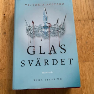Glas Svärdet - En spännande bok med en dramatisk krona på omslaget, skriven av Victoria Aveyard. Perfekt för dig som gillar fantasy och äventyr. Boken är utgiven av Modernista och passar unga vuxna som vill försvinna in i en annan värld.