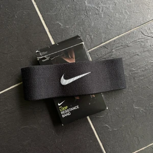 Svart träningsband från Nike - Säljer ett svart loop resistance band från Nike med tydlig vit logga. Aldrig använd men tagits ut ur paketet som slits. 