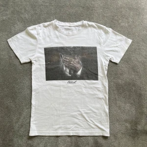 T-shirt med tryck - Vit t-shirt med ett stort svartvitt tryck på bröstet! Skick 8/10 & Storlek XS. Hör av er vid frågor!