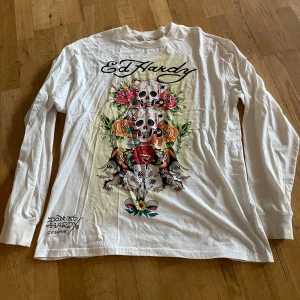 Vit långärmad tröja med tryck från Ed Hardy -  Ed Hardy Black vit långärmad med stort färgglatt tryck av dödskallar, framsidan. Köpte för 500 säljer för 350!
