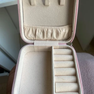 Rosa smyckesask med dragkedja - Söt och praktisk smyckesask i ljusrosa med dragkedja. Insidan har fack för ringar, örhängen och halsband samt en liten ficka. Perfekt för att organisera dina smycken hemma eller på resan.