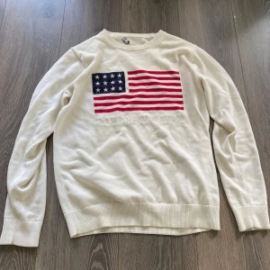 Vit stickad tröja med amerikansk flagga från GANT - Säljer en vit stickad tröja från GANT, strl S, bra skick, som är i slim-fit 