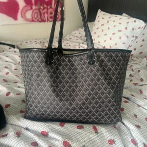 superfin väska - Säljer en snygg svart och grå shoppingväska med grafiskt mönster. Väskan har två långa handtag och är perfekt för att bära med sig allt man behöver. Enkel och stilren design som passar till många tillfällen. Skriv gärna vid frågor!!🤩