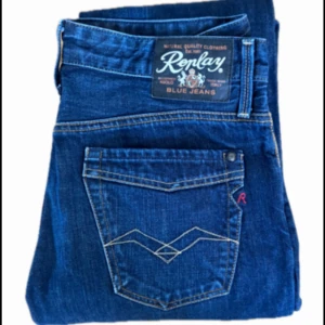 Blå Replay jeans med raka ben - Säljer ett par klassiska blå jeans från Replay med raka ben och snygga kontrastsömmar. Jeansen har fem fickor, dragkedja och knapp i gylfen samt tydlig Replay-logga på bakfickan. Perfekta för dig som gillar tidlös denimstil. Tveka inte på att hör av dig vid frågor!