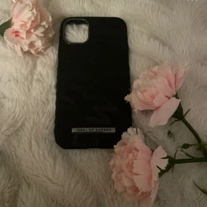 Svart mobilskal från Ideal of Sweden, iPhone 11 - Säljer ett stilrent svart mobilskal från Ideal of Sweden. Skalet har en enkel och clean design med en liten metallbricka med varumärket på nedre delen. Passar perfekt för dig som vill ha ett snyggt och diskret skydd till mobilen. (Bud gärna)