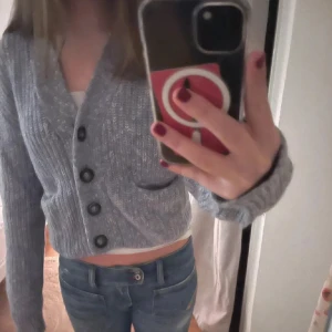 Ljusgrå stickad kofta från HOPE - Säljer en ljusgrå stickad kofta från HOPE med stora svarta knappar framtill. Perfekt för lager-på-lager och enkel att matcha med jeans eller kjol.