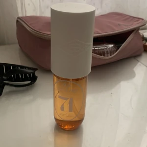 Sol de Janeiro  - Säljer en elegant parfymflaska No. 7 från & Other Stories. Flaskan är genomskinlig med bärnstensfärgad vätska och har ett stort vitt lock. Minimalistisk design som passar perfekt på sminkbordet.